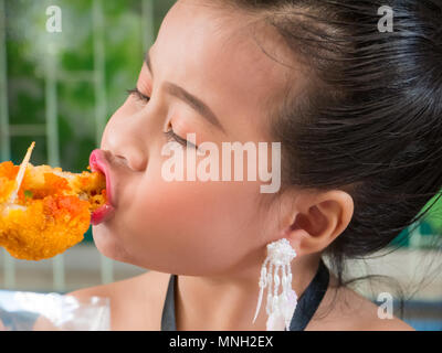 Carino bambina di mangiare il delizioso fritto di pollo Foto Stock