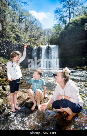 Quattro le cascate a piedi vicino Pontneddfechan in Brecon Beacons - una famiglia gioca nell'acqua in Sgwd yr Eira falls (cadute di neve) sulla Rive Foto Stock