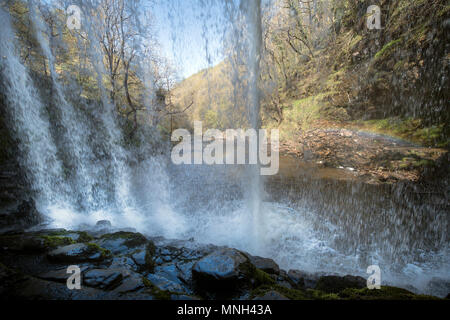 Quattro le cascate a piedi vicino Pontneddfechan in Brecon Beacons - cortina di acqua da dietro il Sgwd yr Eira falls (cadute di neve) sul Fiume Foto Stock