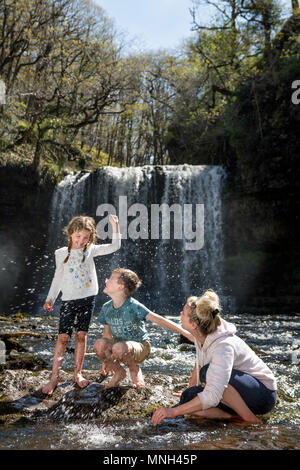 Quattro le cascate a piedi vicino Pontneddfechan in Brecon Beacons - una famiglia gioca nell'acqua in Sgwd yr Eira falls (cadute di neve) sulla Rive Foto Stock