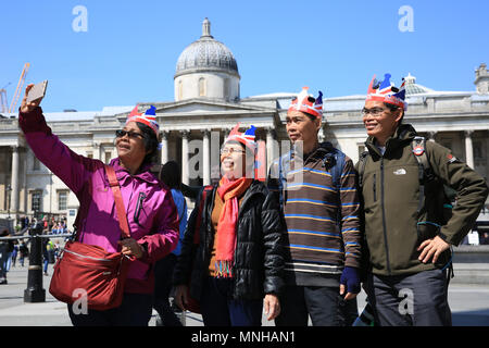 Londra, 17 maggio 2018. Un gruppo di turisti asiatici, in un tour attorno alla capitale, prendere obbligatoria di Trafalgar Square selfie e dire loro di guardare avanti per vivere l'atmosfera per il Royal Wedding. Essi hanno avuto nello spirito delle cose che indossa Union Jack corone di carta. Intorno a Londra, per i turisti e per i londinesi sembrano entrare nello spirito di tutte le cose "Royal Wedding" come bandiere e jack dell'Unione appaiono in giro per la capitale di credito Imageplotter: News e sport/Alamy Live News Foto Stock