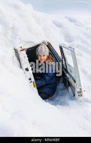 Adorabile bambina all'aperto sulla splendida giornata invernale in un auto di coprire con neve dopo la nevicata Foto Stock