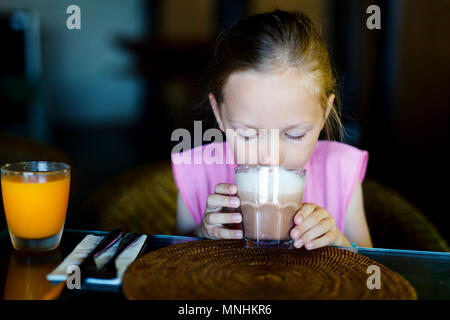 Adorabile bambina in ristorante a bere cioccolata calda Foto Stock