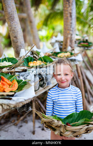 Bambina tenendo la piastra intessute con alcuni enti locali del sud pacifico per origine del cibo servito in conchiglie giganti Foto Stock