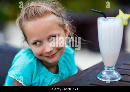 Adorabile bambina bere frullato fresco a outdoor cafe sul giorno di estate Foto Stock