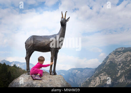 Ragazza alla statua di Zlatorog, leggendario bianco camoscio buck, o in alcune storie sloveno steinbock, che ha avuto il suo regno nelle alture del monte Triglav, Slovenia Foto Stock