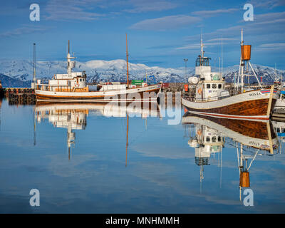 13 Aprile 2018: Husavik, Islanda. Il porto di Husavik nel nord dell'Islanda, con whale-watching navi riflessa nell'acqua calma. Foto Stock