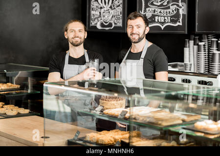 Ritratto di due baristi bello in uniforme in piedi insieme nel panificio negozio Foto Stock