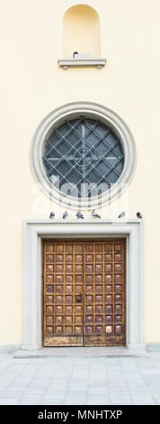 Vecchia porta di legno e la finestra rotonda con griglia metallica. Stormo di piccioni si siede sopra allo sportello Foto Stock