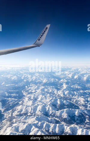 Alpi, Europa - dicembre 2017: Ala della Ryanair aereo Boeing 737 volare sopra le montagne delle Alpi in Europa Foto Stock