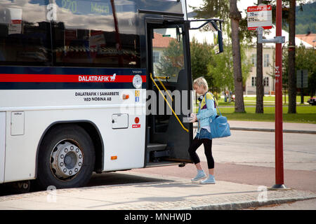 Una giovane donna a salire su un autobus a Rättvik stazione ferroviaria con destinazione Mora gestito da Nobina per Dalatrafik. Posizione: Rättvik, Svezia - 7 giugno 2 Foto Stock