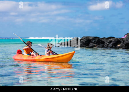 Kids godendo paddling in colorate di rosso il kayak al Tropical Ocean acqua durante le vacanze estive Foto Stock