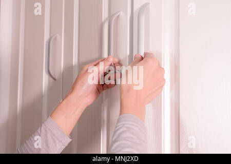 Le donne sono le mani Aprire l'armadio/sportello di armadietto, bianco porta in legno Foto Stock