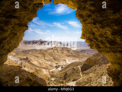 Una vista da una grotta incorniciare una solitaria collina e montagna in background,un sentiero sul lato.un bel cielo blu chiaro e bianco sopra cloudes.da Israele Foto Stock