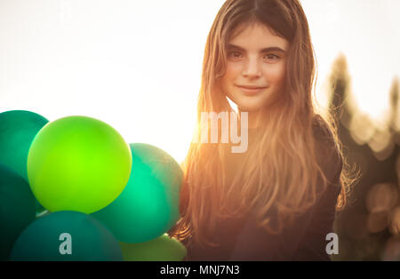 Ritratto di una ragazza carina con aria palloncini all'aperto in serata dolce della luce del sole, festeggia il compleanno, vacanze e concetto di divertimento Foto Stock