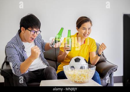 La gente guarda il calcio. Asian Football Supporters guardare partite di calcio in televisione a casa con felice commozione. Foto Stock