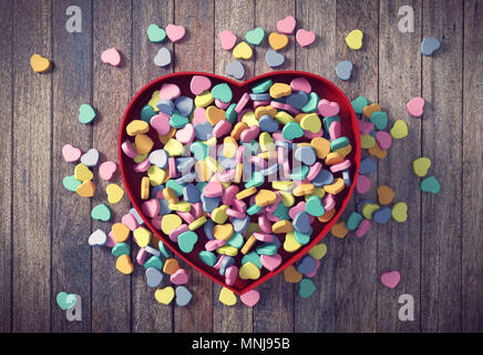 Colorato Valentines mini cuori nel cuore rosso scatola su uno sfondo di legno, rendering 3D Foto Stock