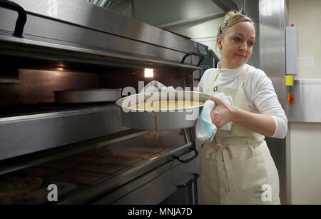 Claire Ptak, proprietario di violetta panificio a Hackney, a est di Londra, porta la parte della torta per le nozze del principe Harry e Meghan Markle fuori del forno nelle cucine a Buckingham Palace a Londra. Foto Stock