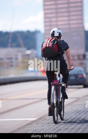 Amatoriale ciclista femmina con zaino preferiscono un attivo uno stile di vita sano ed escursioni in bicicletta lungo la pista ciclabile lungo la carreggiata in down town del mo Foto Stock