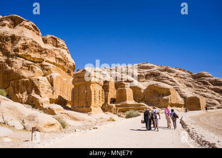 I turisti a piedi sul sentiero in Petra con tombe e templi scolpiti in pietra arenaria, Wadi Musa, Maan Governatorato, Giordania Foto Stock