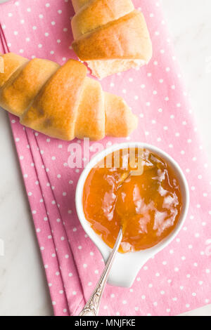 Confettura di albicocche gelatina e croissant sul tovagliolo. Vista dall'alto. Foto Stock
