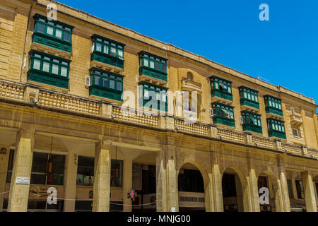 La Valletta, Malta libertà edificio quadrato. Vista giorno della tradizionale pietra calcarea maltese edificio con balconi di verde e negozi al top della Repubblica Street. Foto Stock