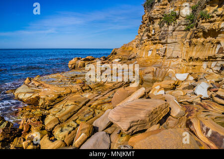 Splendidamente paterned Hawksbury scogliera di arenaria a Maitland Bay, decorative di linee di colore marrone e le iscrizioni sono state formate da ricchi di ferro e di acqua sono kn Foto Stock
