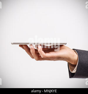 Imprenditore detiene digitale compressa contro uno sfondo grigio. Foto Stock