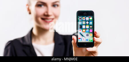 Giovane donna trattiene il nero per Apple iPhone 5 display in mano. Foto Stock