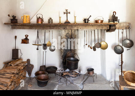 Vista frontale di uno stile retrò cucina rustica con caminetto aperto, utensili di cottura, padelle e varie altre attrezzature per cucina Foto Stock