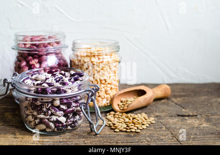 Assortimento di organico secco fagioli e lenticchie in vasetti di vetro su tavola in legno rustico. Varietà di legumi di greggio. Dieta bilanciata, cucina vegetariana e pulire Foto Stock