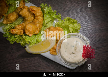 I gamberi fritti su una piastra con salsa e su uno sfondo di legno Foto Stock