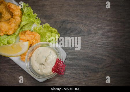 I gamberi fritti su una piastra con salsa e su uno sfondo di legno Foto Stock