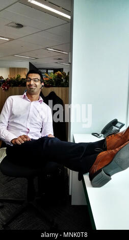 Uomo seduto in ufficio con piedi sulla scrivania Foto Stock