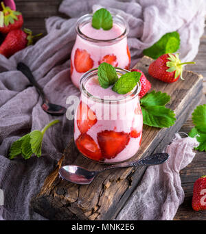 I frullati di fragole fresche e yogurt in un vasetto di vetro sul grigio di una tavola di legno Foto Stock