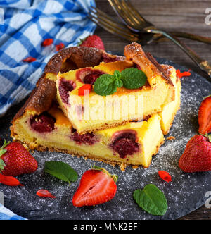 Pezzi di torta di ricotta e fragole su un nero grafite piastra, vista dall'alto Foto Stock