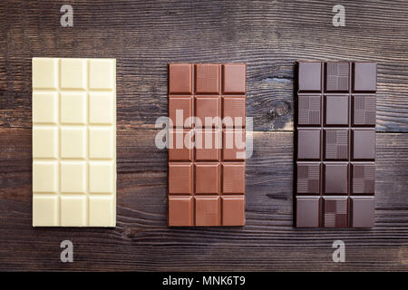 Deliziosi dolci e barrette di cioccolato su sfondo di legno Foto Stock