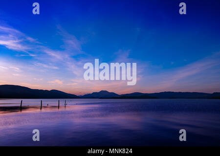 Loch Lomond tramonto, colori vivaci che riflette nella tranquilla loch Foto Stock