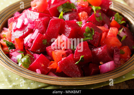 Insalata di barbabietole con cipolle, pomodori e le erbe aromatiche con olio di oliva close-up su una piastra orizzontale. Foto Stock