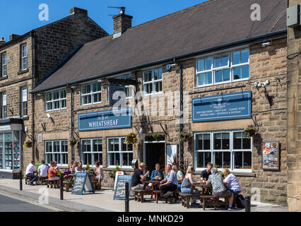 La gente seduta al di fuori del Pub Wheatsheaf su Bridge Street nel centro della città, Bakewell, Derbyshire, England, Regno Unito Foto Stock