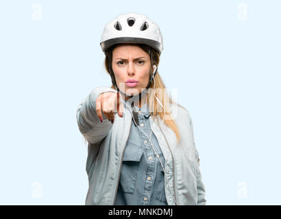 Giovane donna con il casco protettivo e gli auricolari in rivolta verso la parte anteriore con un dito Foto Stock