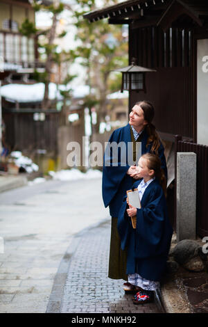 La famiglia di madre e figlia di indossare uno yukata tradizionale giapponese in kimono street di onsen resort città in Giappone andando al pubblico spa Hot Spring. Foto Stock