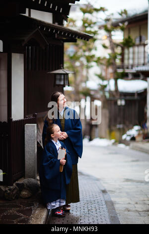 La famiglia di madre e figlia di indossare uno yukata tradizionale giapponese in kimono street di onsen resort città in Giappone andando al pubblico spa Hot Spring. Foto Stock