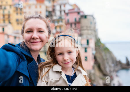 Madre e figlia tenendo selfie alla vista panoramica del villaggio colorato in Cinque Terre, Italia sullo sfondo Foto Stock