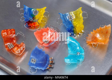 Molte colorate bretelle dentali o i fermi per i denti su sfondo metall, primo piano Foto Stock