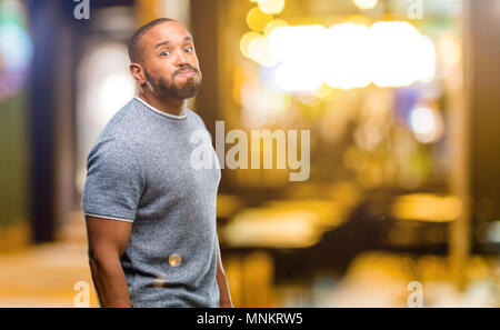 African American uomo con barba sbuffando fuori le guance, avendo divertimento rendendo divertente faccia di notte Foto Stock