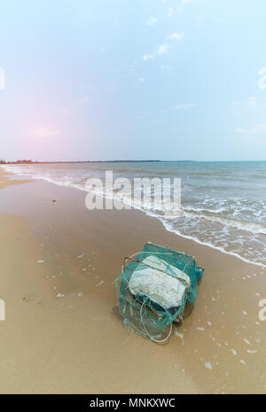 Vecchia gabbia di granchio con schiuma sulla spiaggia Foto Stock