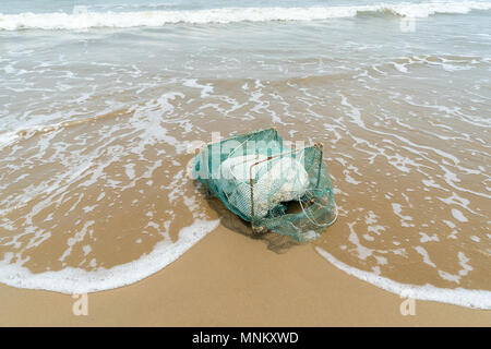 Vecchia gabbia di granchio con schiuma sulla spiaggia Foto Stock