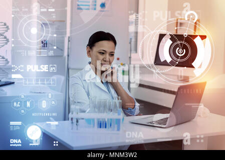 Allegro medico sorridere mentre guardando lo schermo del suo computer portatile moderno Foto Stock