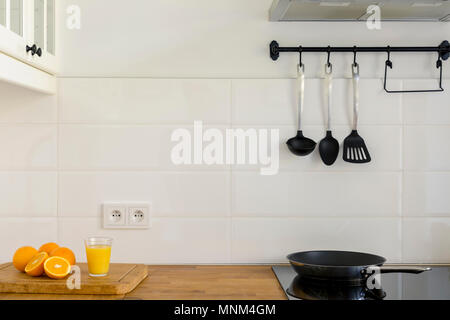 Succo di arancia sul bancone in legno in cucina bianca interno con cucchiai sul gancio. Foto reale Foto Stock